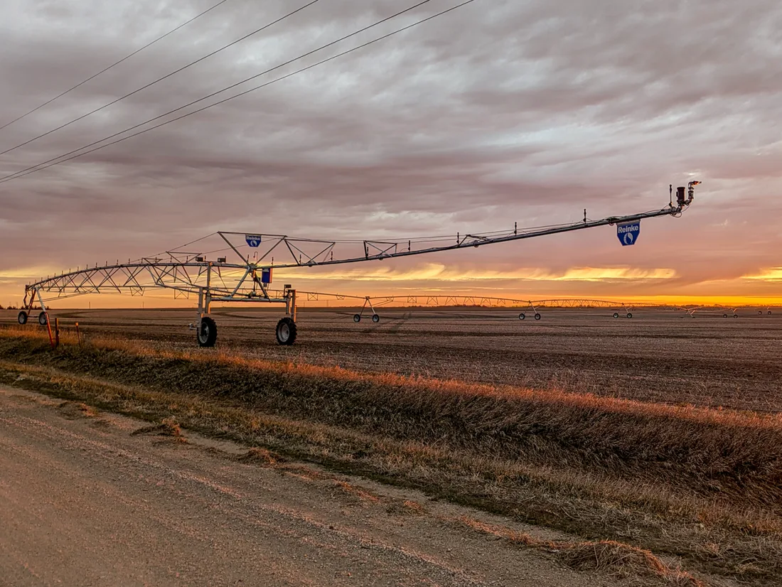 Reinke center pivot silhouetted against a sunset over a field