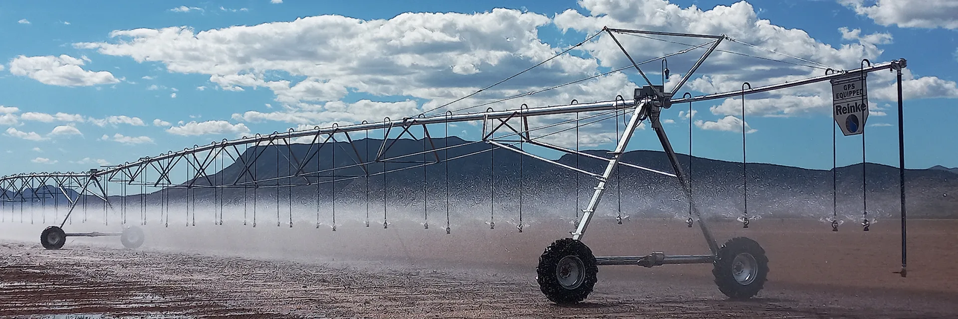 Water spraying from a Reinke center pivot across a crop field